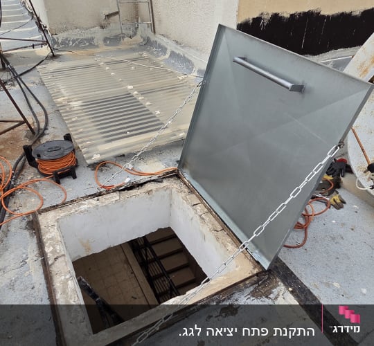 פתח גג עם מכסה מתכת, כבלים וציוד עבודה